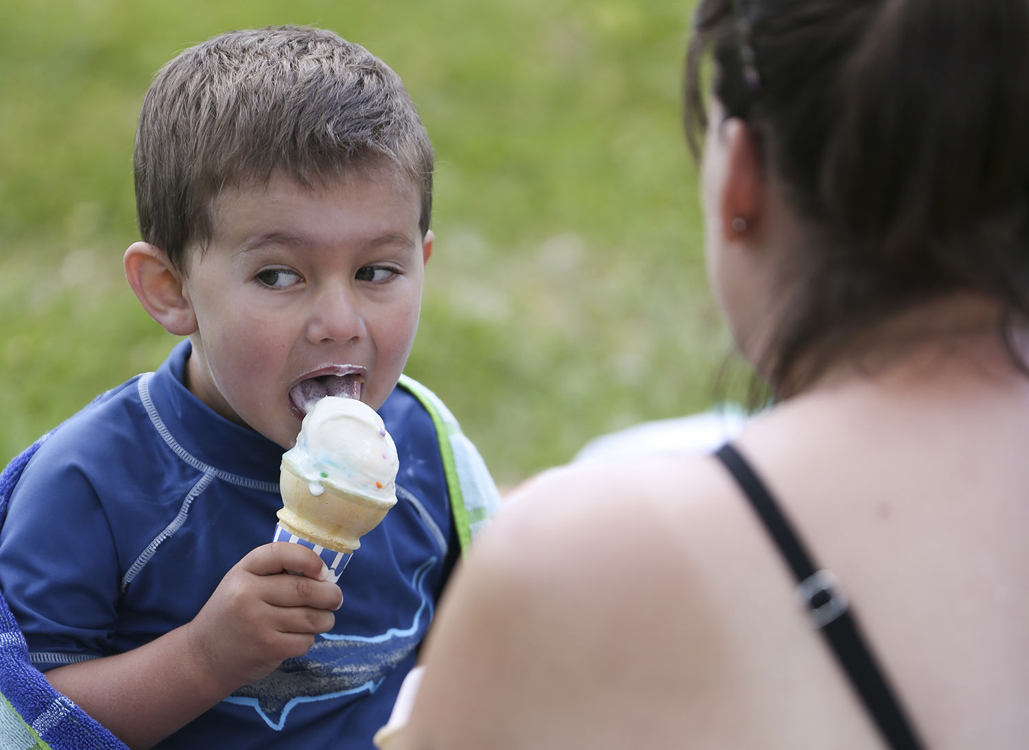 Briggs Gunderman, 3, eats sprinkles ice cream with his mom Teresa under the shade of a tree